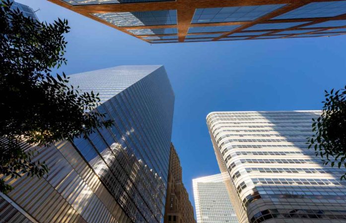 Immeubles de bureaux modernes vus d'en bas pour illustrer comment investir dans la pierre valeur refuge France via les SCPI.
