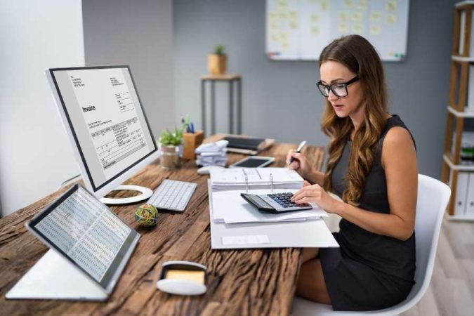 Une professionnelle utilise une calculatrice et un écran d'ordinateur pour gérer des aspects administratifs encadrés par la convention fiscale France Émirats.