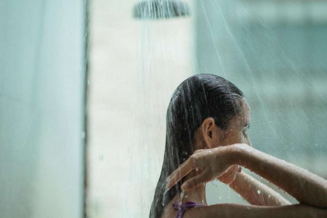 Une femme prend une douche relaxante sous un jet d'eau régulier.