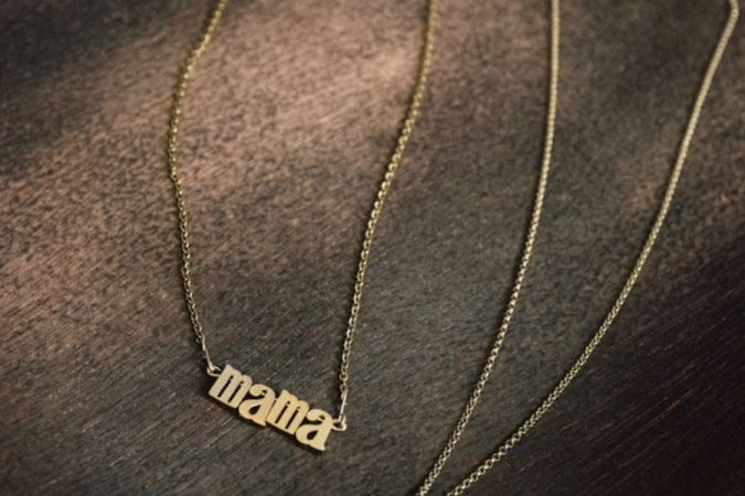 Un collier fin avec un pendentif portant l'inscription "mama", illustrant une élégante chaîne en or jaune.